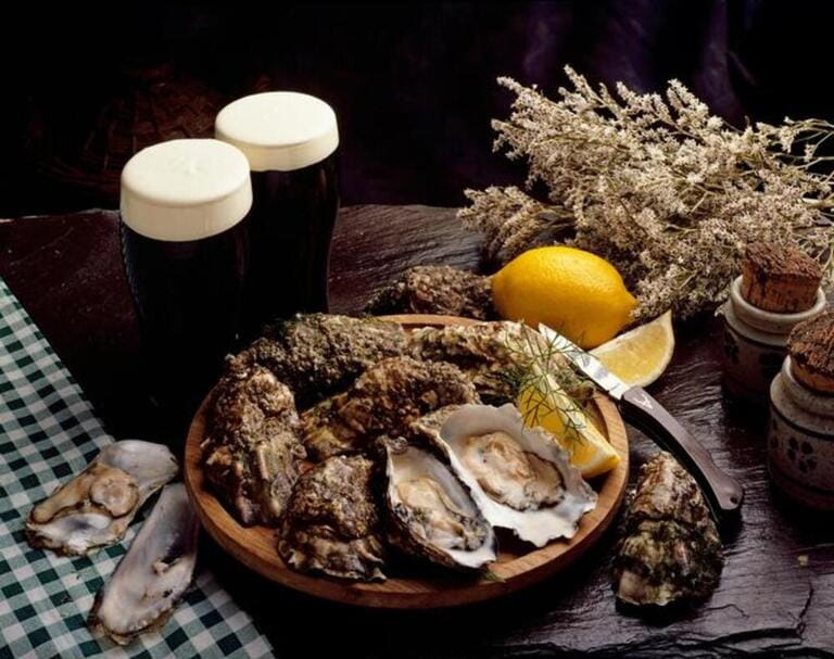 High Angle View Of A Platter Of Oysters With Glasses Of Beer On A Table High Angle View Of A Platter Of Oysters With Glasses Of Beer On A Table