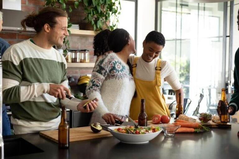 Group of happy diverse female and male friends drinking beer and cooking together in kitchen Group of happy diverse female and male friends drinking beer and cooking together in kitchen
