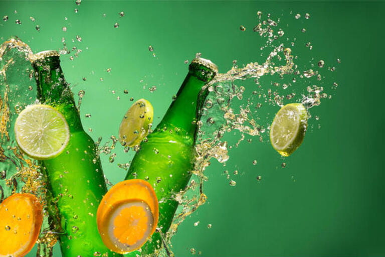 Bottles of fruit beer with splash around on green background. Bottles of fruit beer with splash around on green background.
