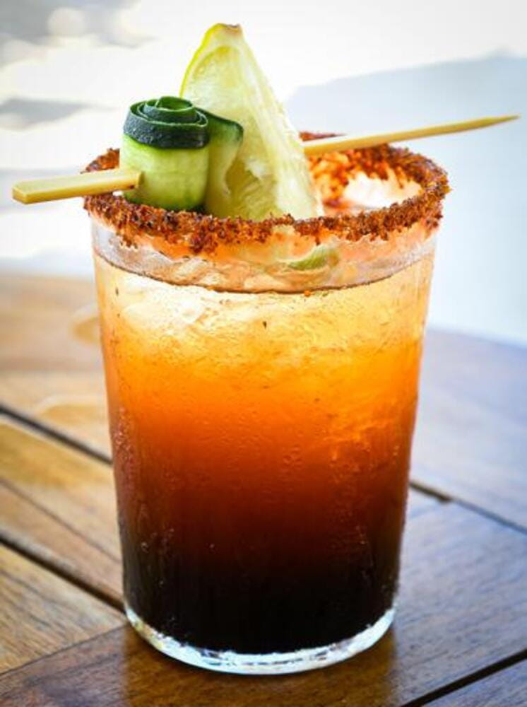 Michelada beer with tomato juice. Clamato with beer on wooden table. Mexican drink. Michelada beer with tomato juice. Clamato with beer on wooden table. Mexican drink.