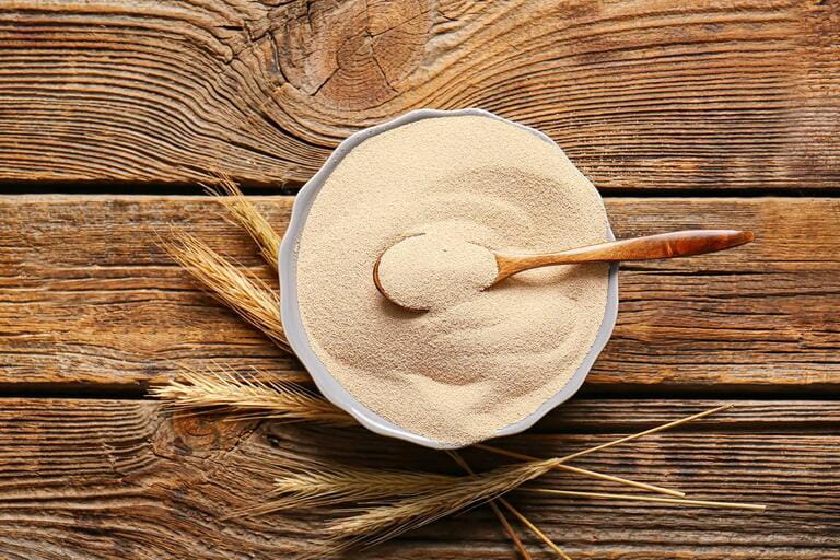 Bowl with active dry yeast on wooden table Bowl with active dry yeast on wooden table