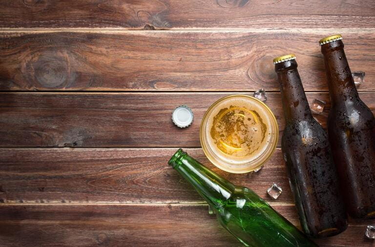 Glass beer with bottle caps and bottles on rustic wooden background, space for text, top view Glass beer with bottle caps and bottles on rustic wooden background, space for text, top view
