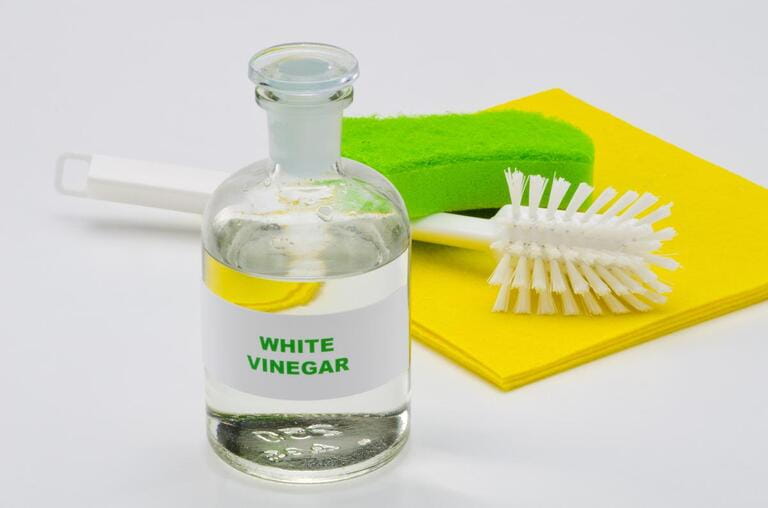 White vinegar in a glass bottle. White background. Organic detergent. White vinegar in a glass bottle. White background. Organic detergent.
