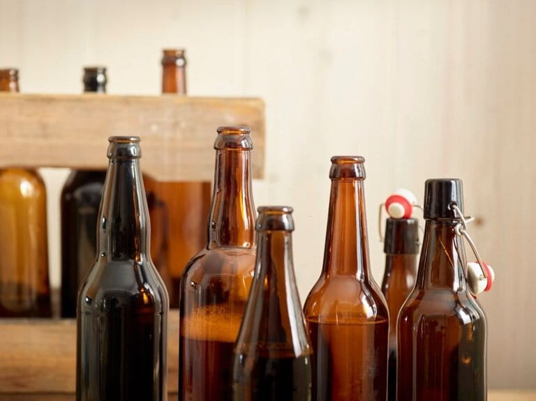 Open beer bottles in front of a wooden crate  Open beer bottles in front of a wooden crate