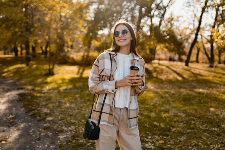 attractive young woman walking in autumn park with coffee wearing checkered coat, sunglasses, happy mood, fashion style trend attractive young woman walking in autumn park with coffee wearing checkered coat, sunglasses, happy mood, fashion style trend