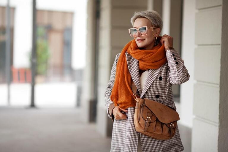 Smiling Woman Outdoor Portrait. Short blonde hair fashion model wears stylish clothes, double-breasted jacket, leather handbag, ochre knitted scarf and glasses. Fashion trend of autumn or spring Smiling Woman Outdoor Portrait. Short blonde hair fashion model wears stylish clothes, double-breasted jacket, leather handbag, ochre knitted scarf and glasses. Fashion trend of autumn or spring
