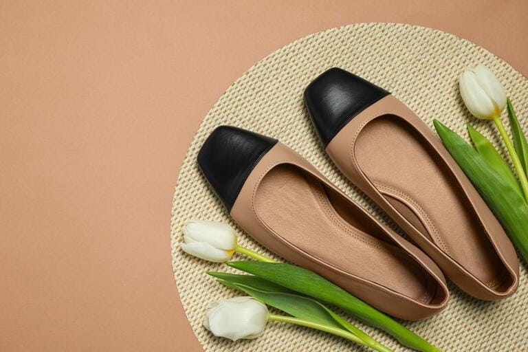 Pair of new stylish square toe ballet flats and beautiful tulips on beige background, flat lay. Space for text Pair of new stylish square toe ballet flats and beautiful tulips on beige background, flat lay. Space for text