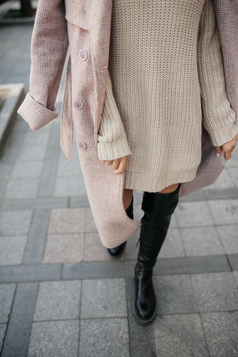 stylish image of urban fashion. knitted beige dress, pink delicate raincoat, black high boots on woman without face. stylish image of urban fashion. knitted beige dress, pink delicate raincoat, black high boots on woman without face.