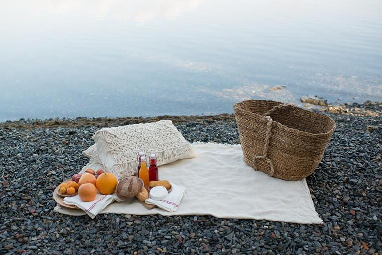 Picnic on the lake shore. Fruit, juice in glass bottles and macrame . Beautiful layout on a light blanket. Picnic on the lake shore. Fruit, juice in glass bottles and macrame . Beautiful layout on a light blanket.