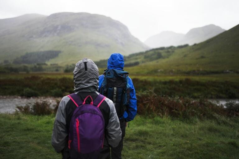 Couple trekking through the rain in the Highlands Couple trekking through the rain in the Highlands