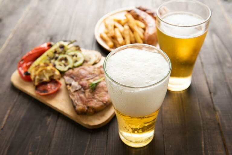 Beer in glass with gourmet steak and french fries on wooden background Beer in glass with gourmet steak and french fries on wooden background