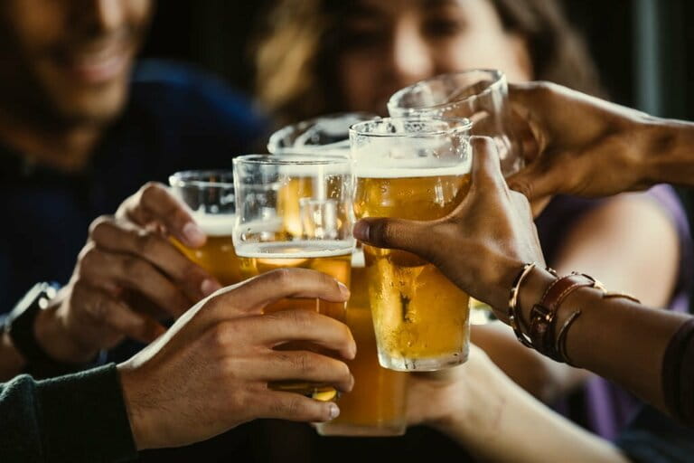 Group of friends toasting beer glasses at table in bar Group of friends toasting beer glasses at table in bar