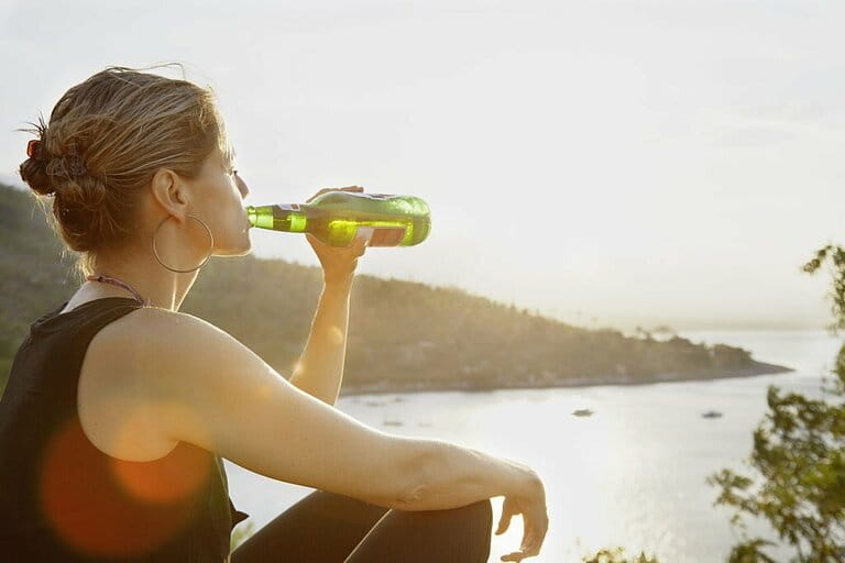Woman enjoying a beer in the sunset up a bay Woman enjoying a beer in the sunset up a bay