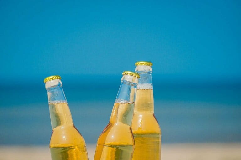 Cold beer bottle on the sand in the sun Cold beer bottle on the sand in the sun