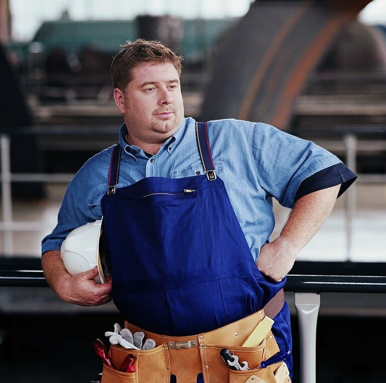 Workman leaning on barrier in power station, arms akimbo Workman leaning on barrier in power station, arms akimbo