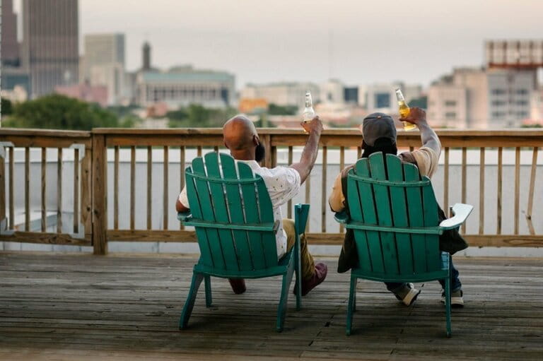 Two Men In Deck Chairs Raising Beer Bottles Two Men In Deck Chairs Raising Beer Bottles