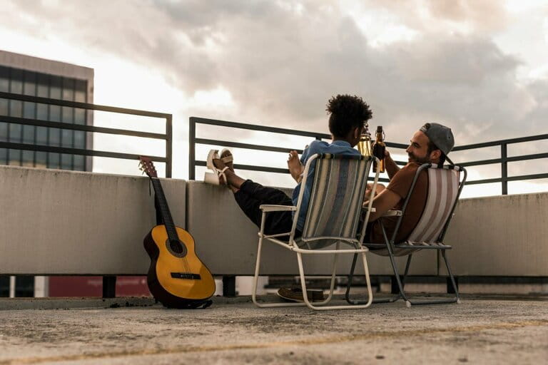 Young couple with beer and guitar sitting on rooftop Young couple with beer and guitar sitting on rooftop