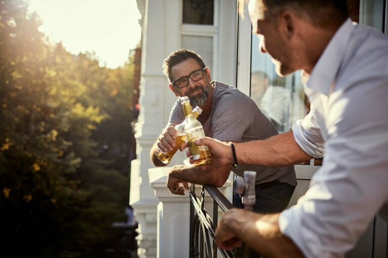 Two mature men having a beer on balcony Two mature men having a beer on balcony