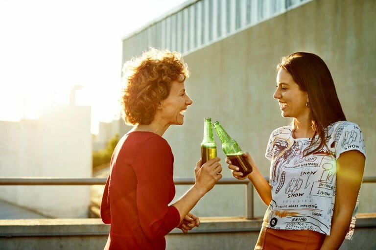 Female friends talking while toasting beer on rooftop Female friends talking while toasting beer on rooftop