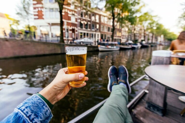 Man relaxing and drinking beer by the canal in Amsterdam, personal perspective view, Netherlands Man relaxing and drinking beer by the canal in Amsterdam, personal perspective view, Netherlands